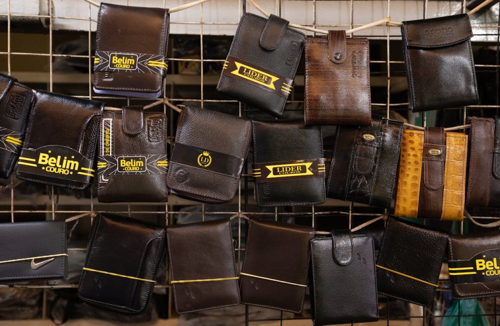 Collection of leather wallets on a market rack, showcasing diverse designs and finishes.